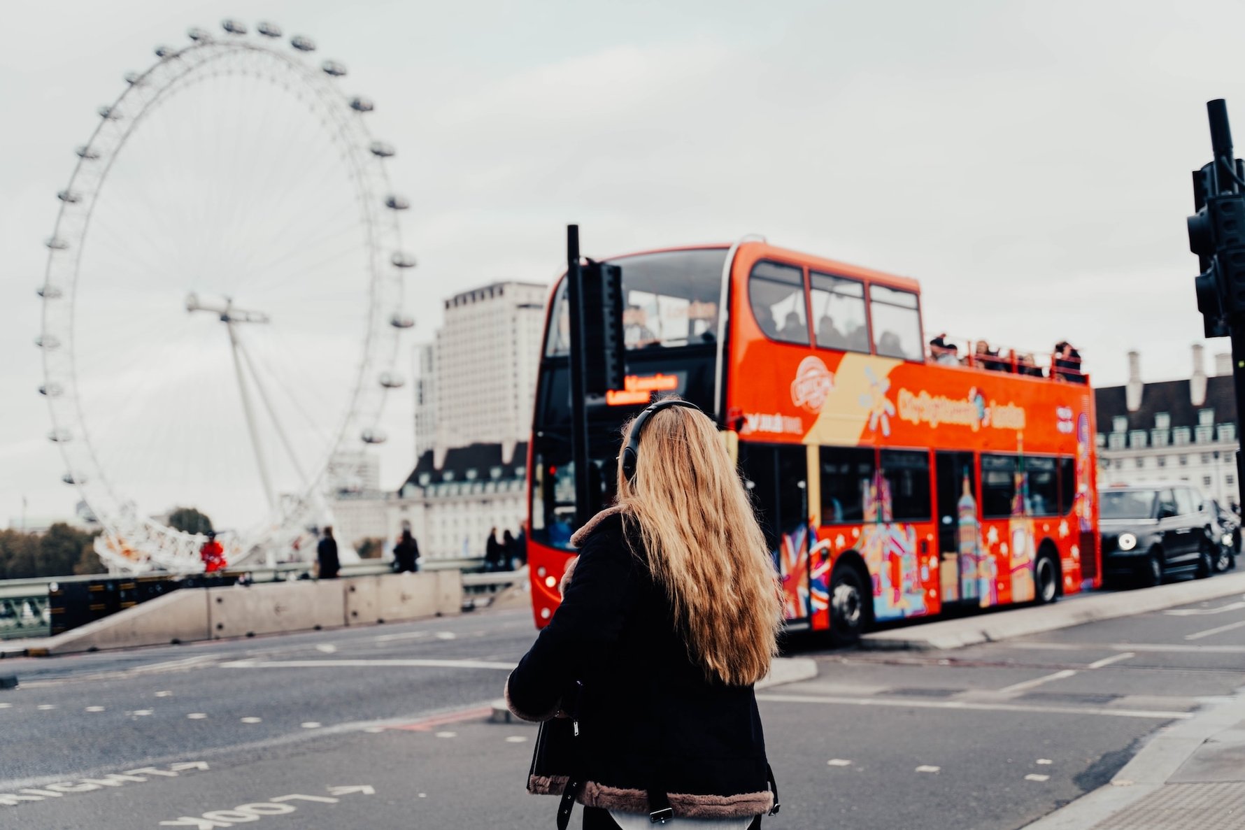 girl standing in front of eye of london and red double decker bus